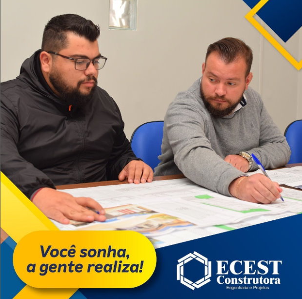 Breno e Guilherme conversando sobre um projeto com a planta numa mesa